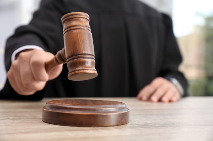 Judge with gavel at wooden table indoors, closeup