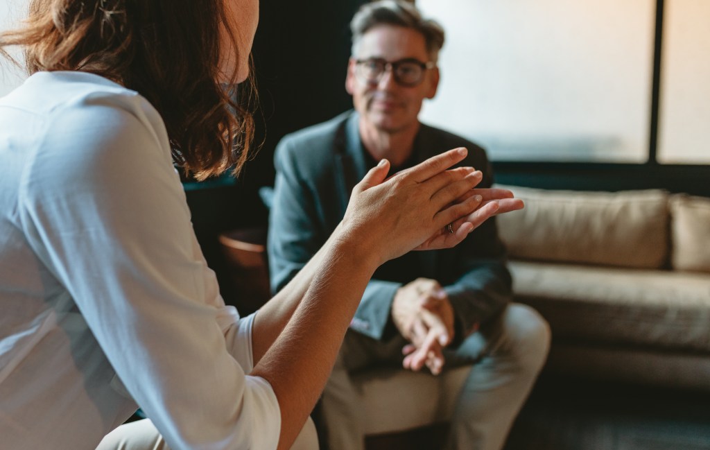 Two business people discussing in office lounge. Businesswoman talking with a male colleague in office lobby.