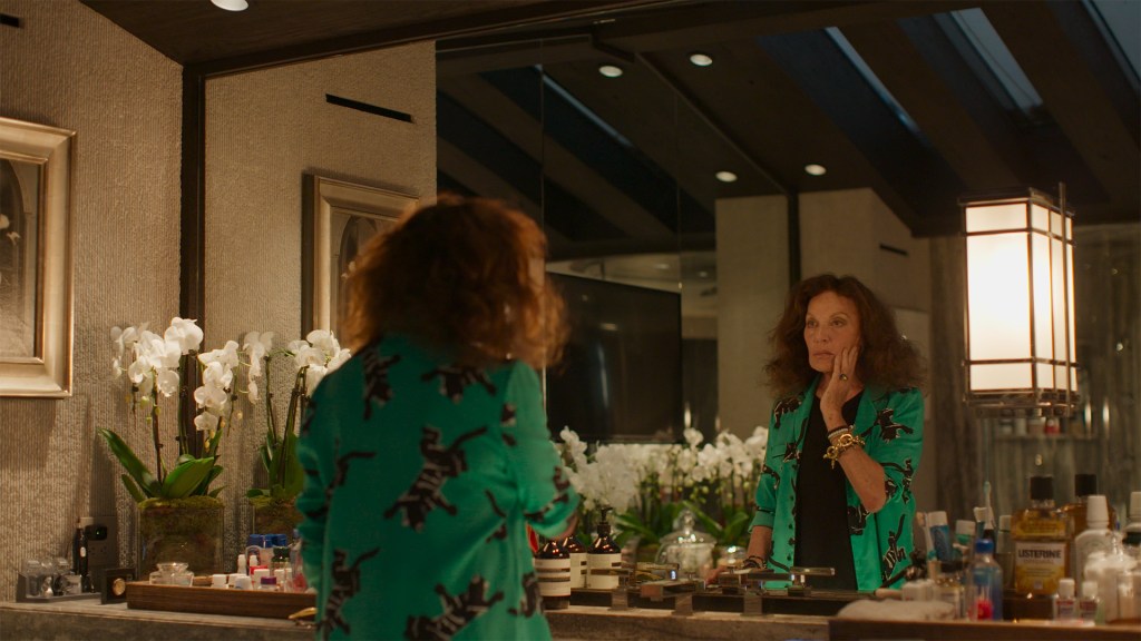 Diane von Furstenberg looking at herself in a mirror, symbol of feminine power in the fashion industry