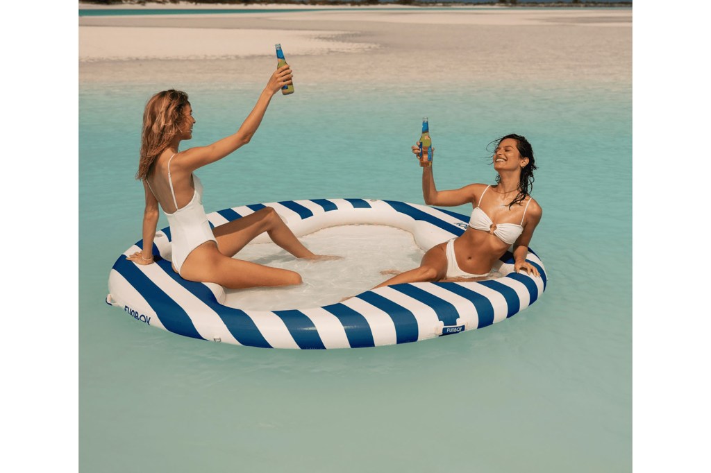 Two women in garments floating on a navy mesh leisure raft in a body of water