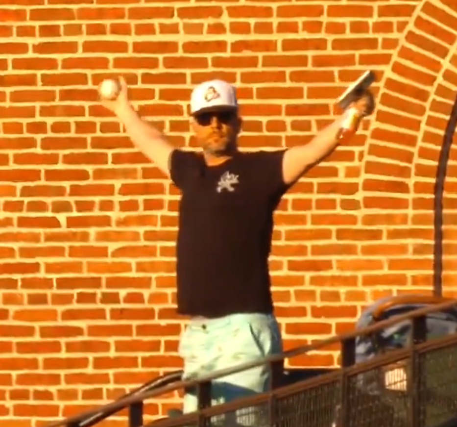 An Orioles fan triumphantly raises his arms after catching a foul ball with only his right hand.