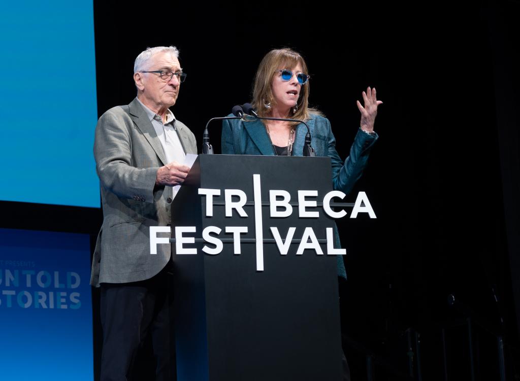Robert De Niro and Jane Rosenthal speaking at a podium during the AT&T Untold Stories event at the 2022 Tribeca Festival in New York City