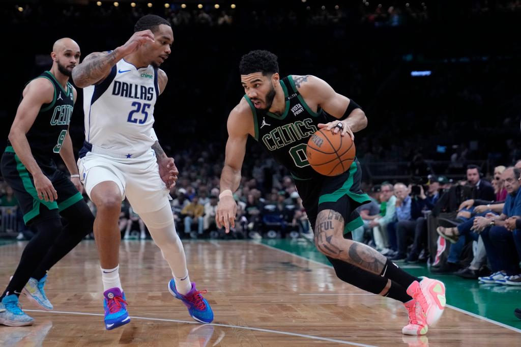 Boston Celtics forward Jayson Tatum dribbling a basketball while Dallas Mavericks forward P.J. Washington attempts to defend during a game in the NBA Finals