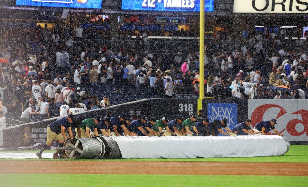 Yankees' grounds crew put the tarp on the field during a rain delay that nearly lasted an hour.