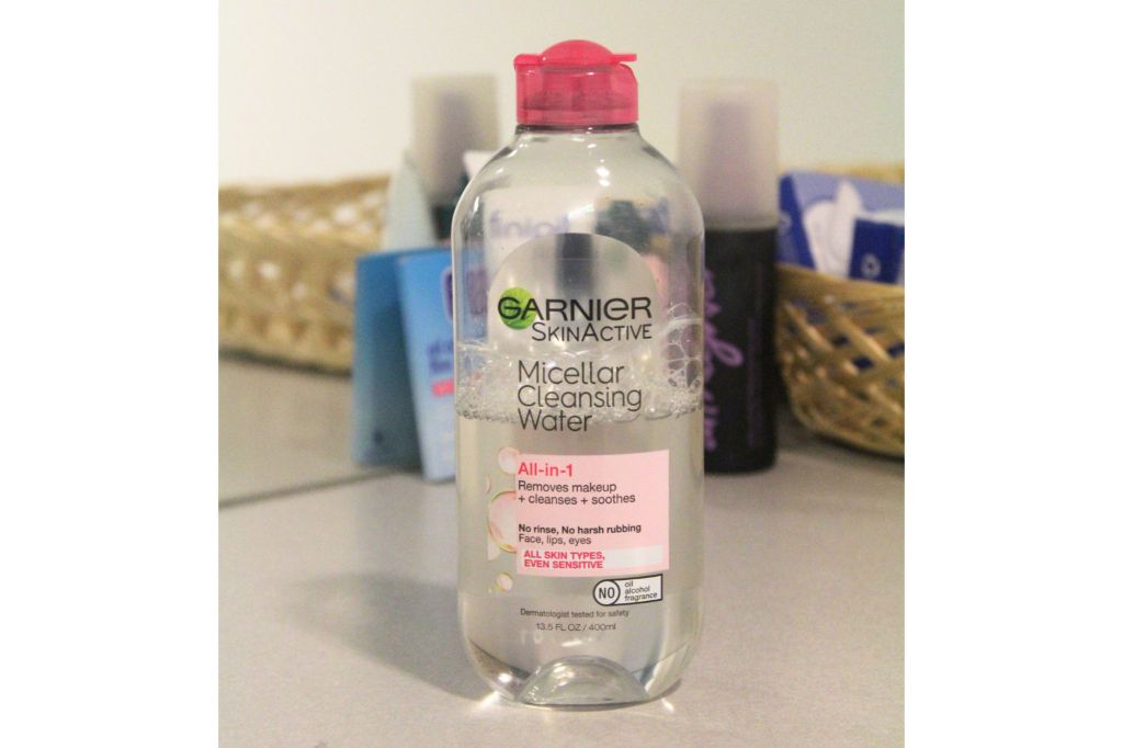 A bottle of micellar water in front of other beauty products.