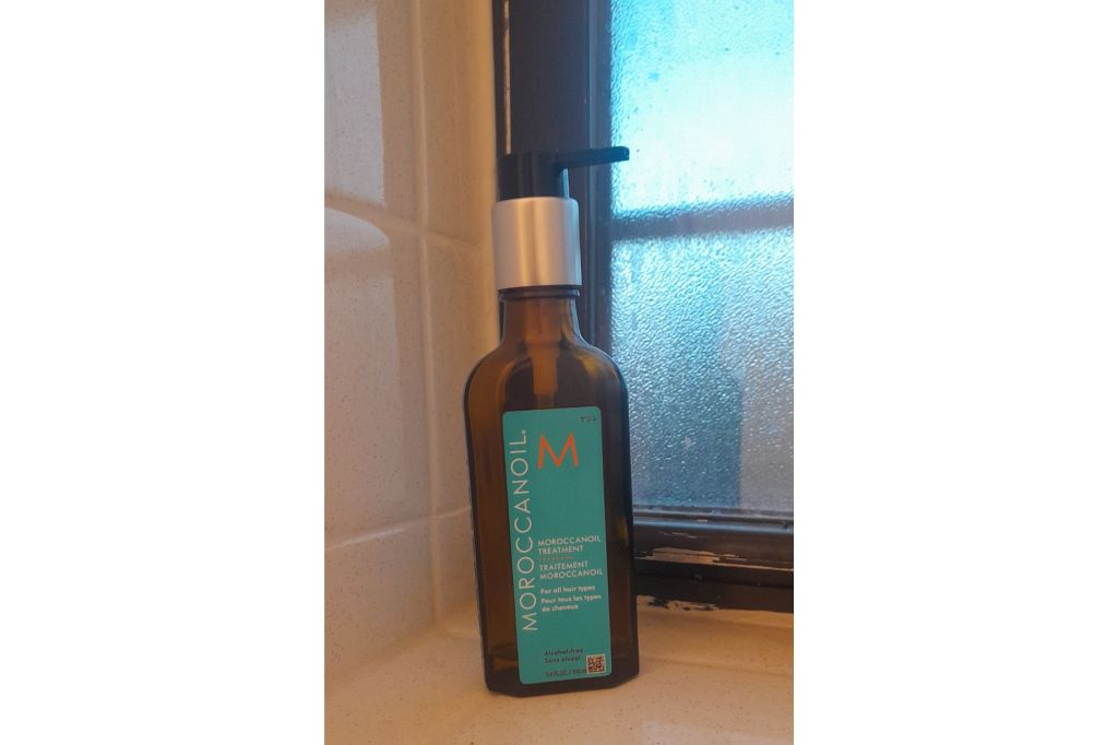 An almost empty bottle of Moroccanoil in a bathroom.