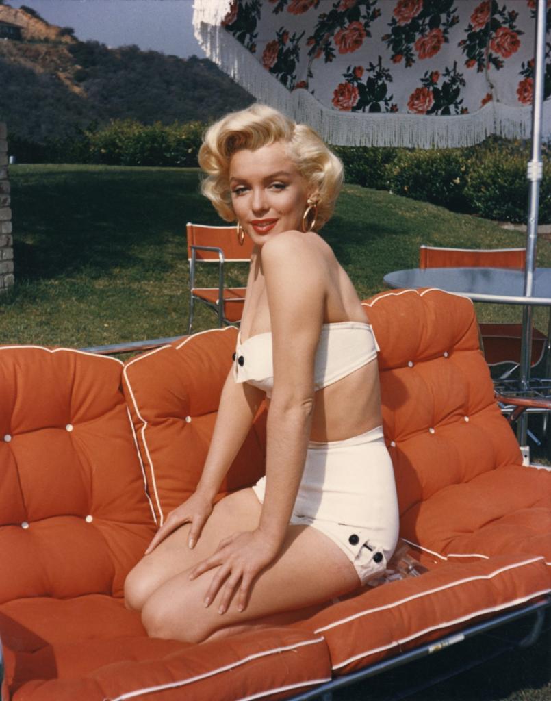 1953 portrait of Hollywood icon, actress Marilyn Monroe, posing on a couch