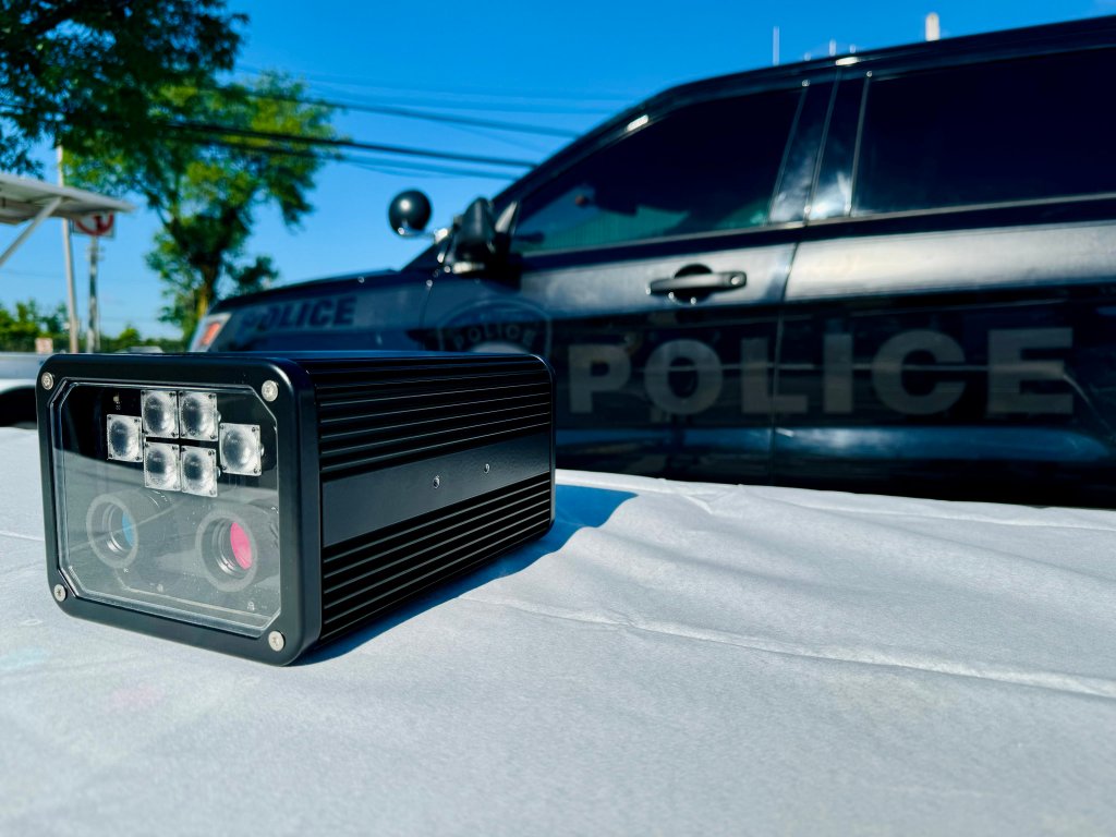 A cop car next to a plate reader. 