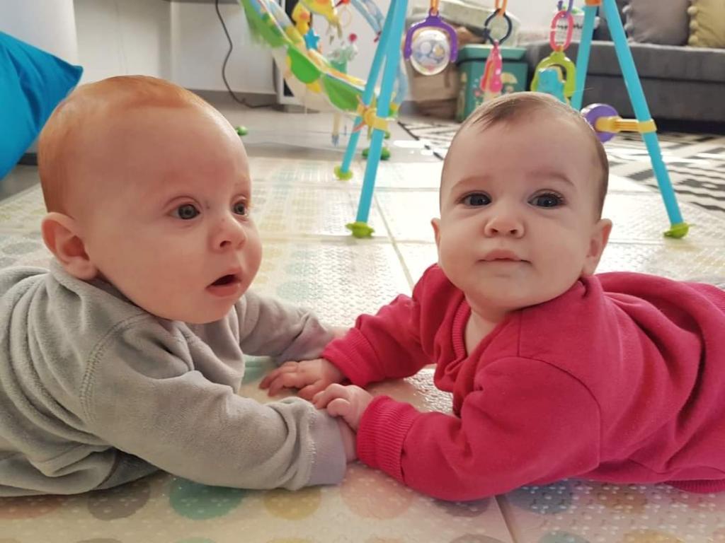 Babies Ariel Bibas (left) and Oren Aharon on their bellies, facing each other, hands touching. 