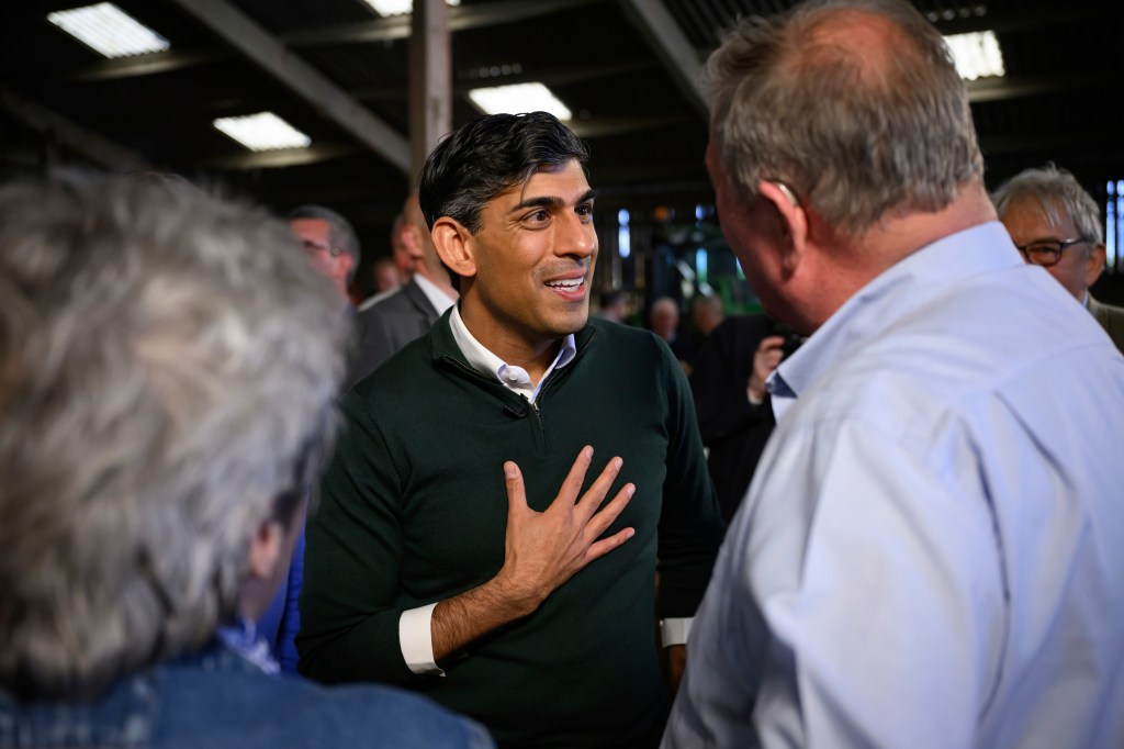 British Prime Minister Rishi Sunak engaging in a conversation with a group of farmers on a farm near Barnstaple, England.