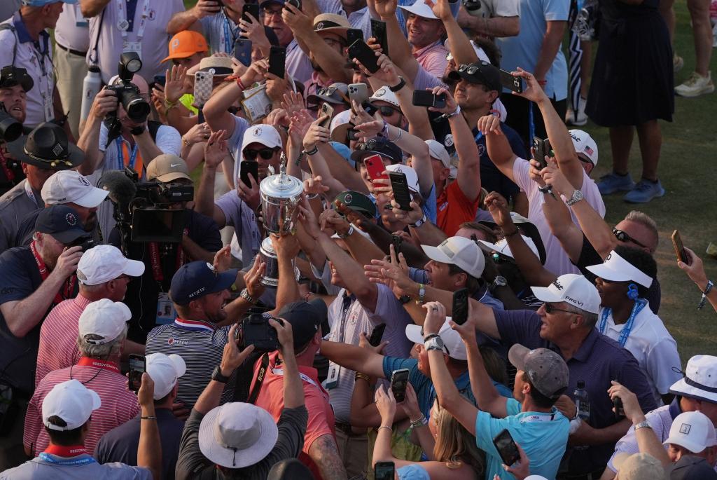 Bryson DeChambeau celebrates with the trophy and fans on the eighteenth fairway after winning the U.S. Open golf tournament on Sunday.