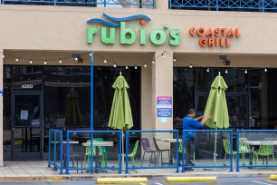 Building Manager closes the umbrellas at Rubio's Costal Grill on Lincoln Blvd in Los Angeles, CA.