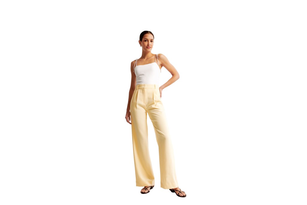 A woman in a white tank top and yellow pants