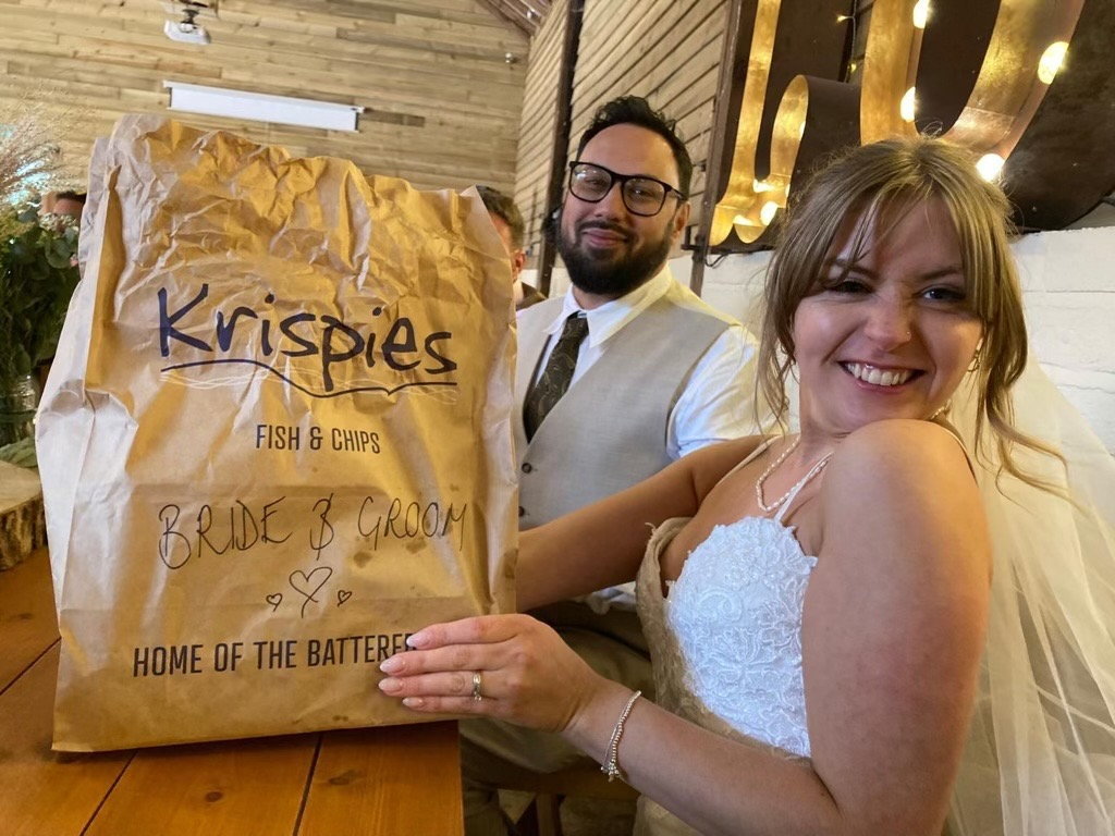 bride and groom with brown paper bag of food