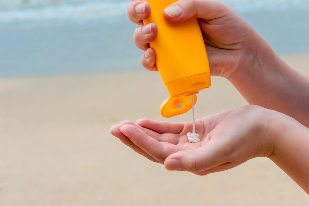 A person pouring sunscreen onto their palm
