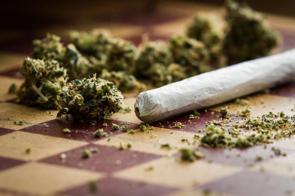 Closeup view of a marijuana joint and buds arranged on a checkerboard table