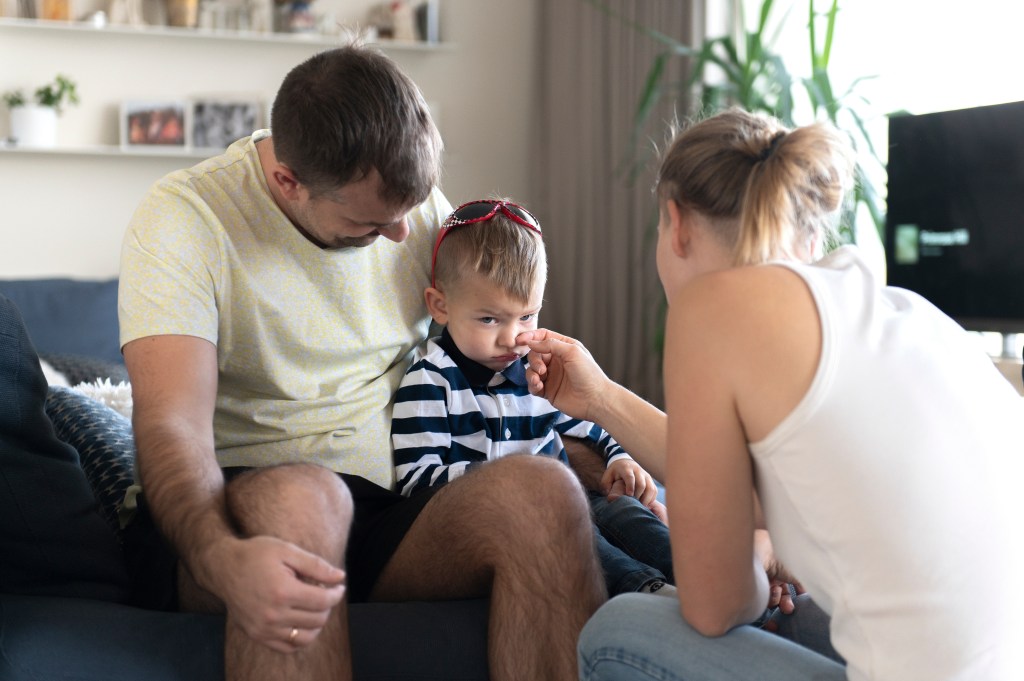 Dad and Mom comfort an crying baby, mother wip his tears