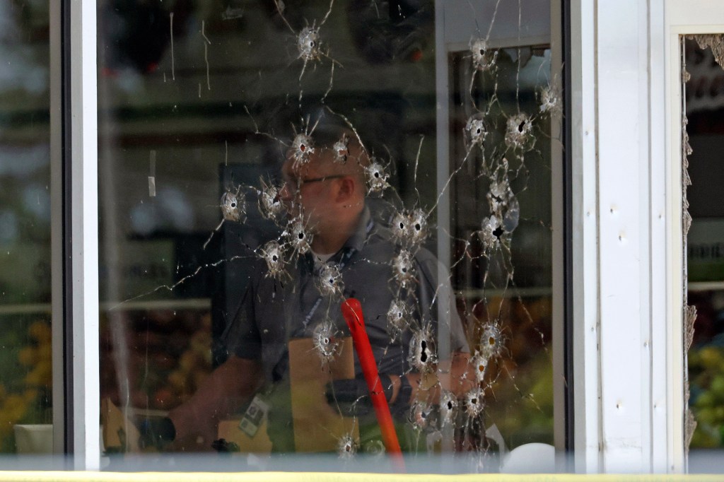 Damage can be seen to a front window law enforcement officers work the scene of a shooting at the Mad Butcher grocery store in Fordyce, Ark., Friday, June 21, 2024.
