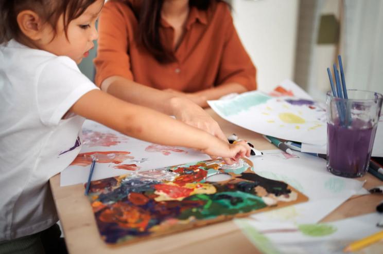 Cute little girl painting with mommy together at home
