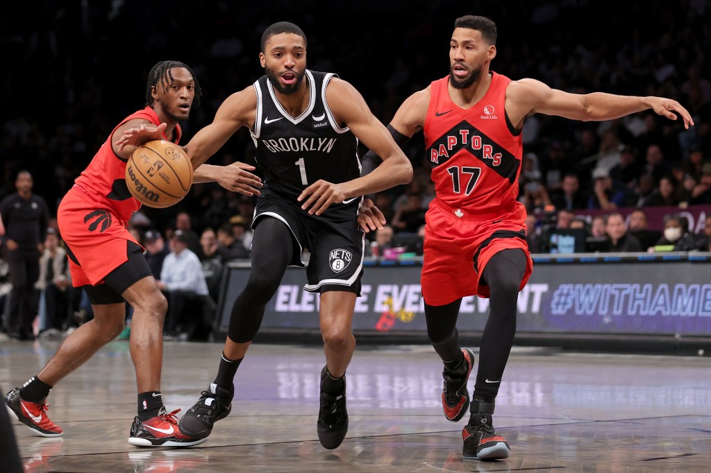 Basketball player Mikal Bridges driving to the basket between Toronto Raptors' Immanuel Quickley and Garrett Temple during an NBA game at Barclays Center