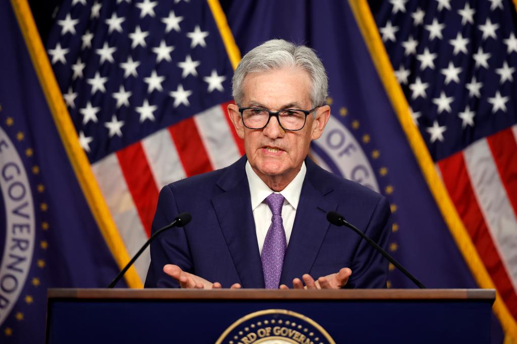 Federal Reserve Bank Chair Jerome Powell announcing unchanged interest rates at a news conference, standing at a podium with microphones