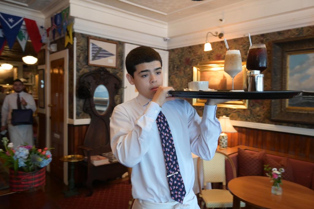 A young waiter holding a tray of drinks.
