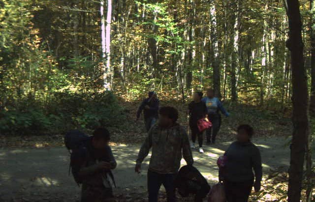 A group of foreign nationals walking through the woods, illegally crossing from Canada into the U.S. in the Swanton Sector