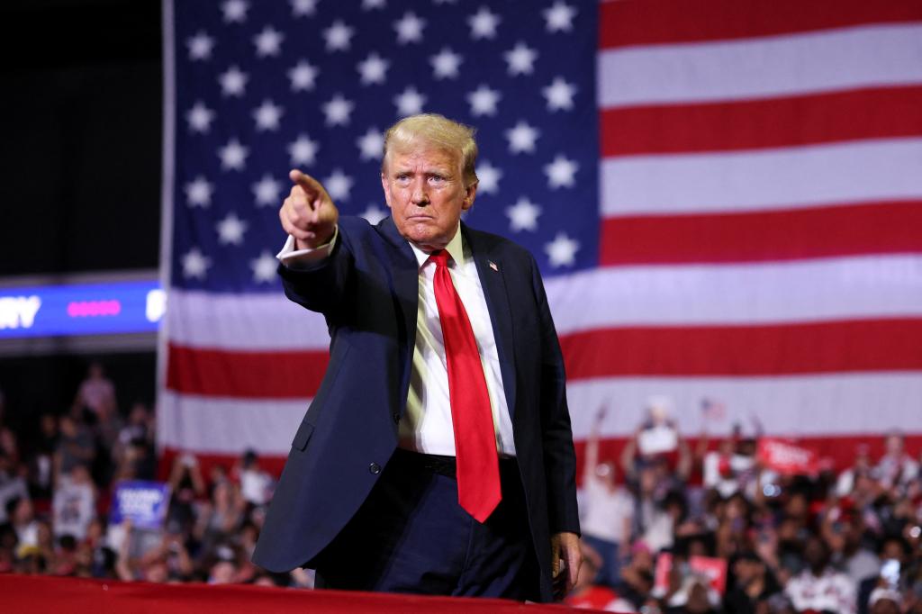 Former U.S. President Donald Trump, dressed in a suit, gesturing towards the camera at a campaign event in Philadelphia, Pennsylvania