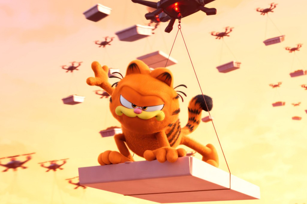 A still from “The Garfield Movie" shows the animated cat riding a package being carried through the air by a drone.