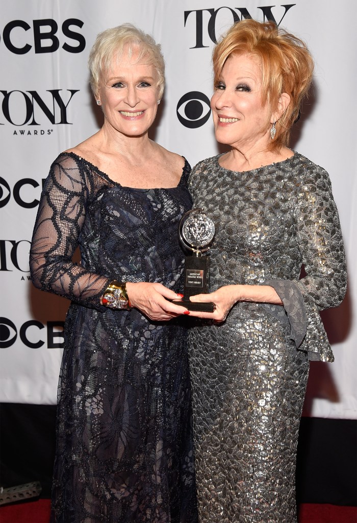 Glenn Close and Bette Midler hold a tony wearing silvery gowns on a red carpet. 