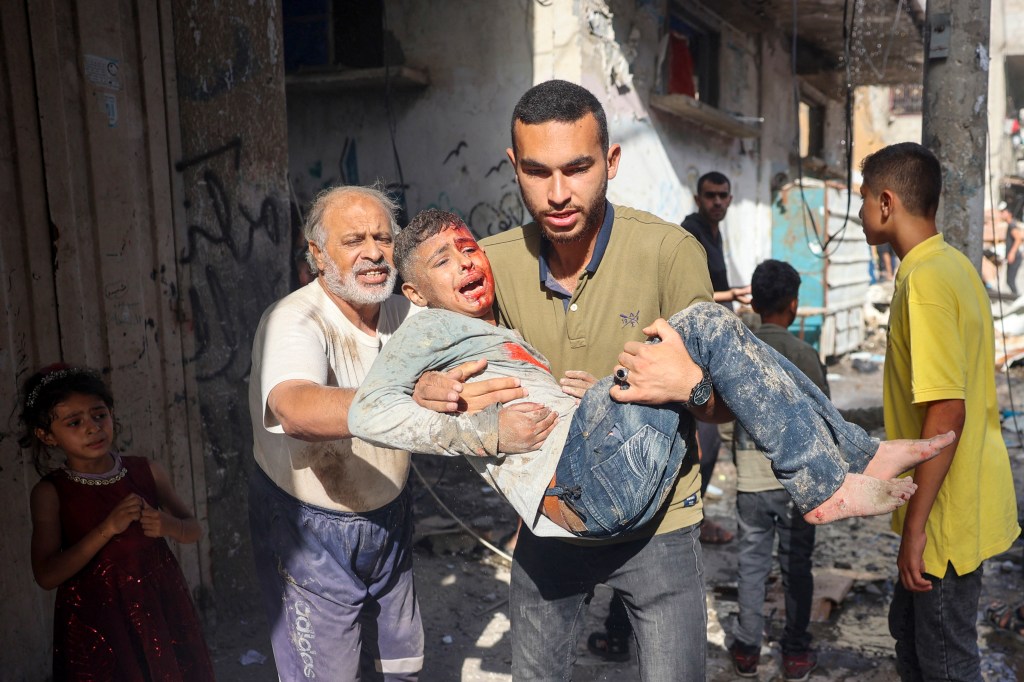 A bloodied child is carried away after being caught in an Israeli airstrike in Gaza. 