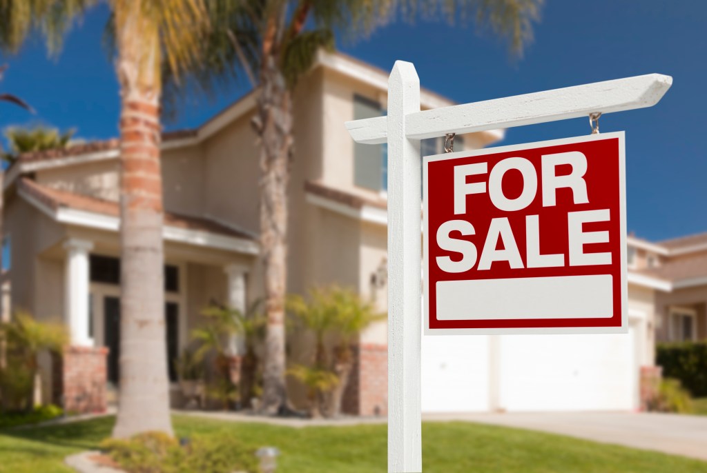 Real estate for sale sign in front of a beautiful new house