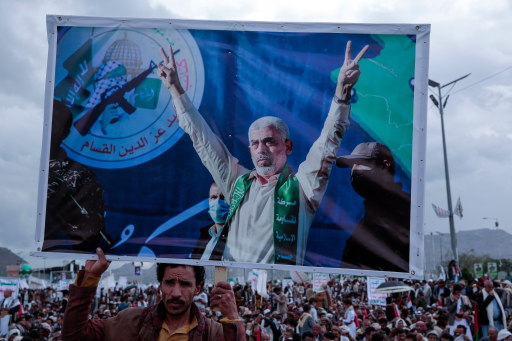 Houthi supporters hold a poster of Yahya Sinwar.