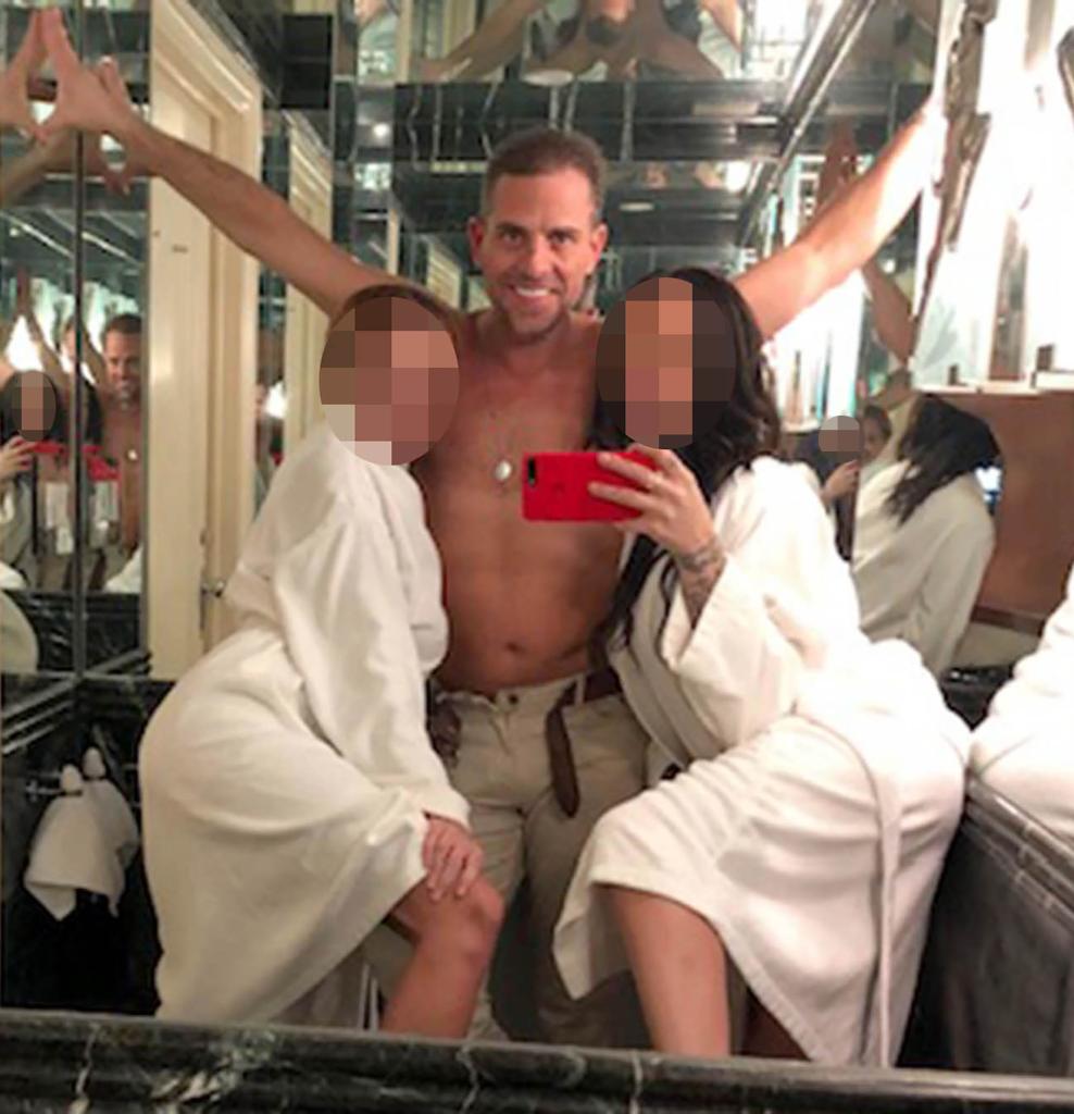 A shirtless Hunter Biden poses with two girls in bathrobes.