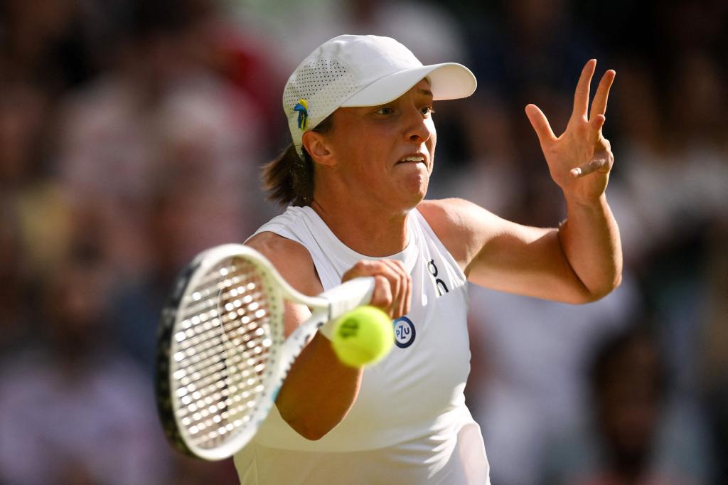 Poland's Iga Swiatek returns the ball to Switzerland's Belinda Bencic during their women's singles tennis match on the seventh day of the 2023 Wimbledon Championships at The All England Tennis Club in Wimbledon, southwest London, on July 9, 2023. 