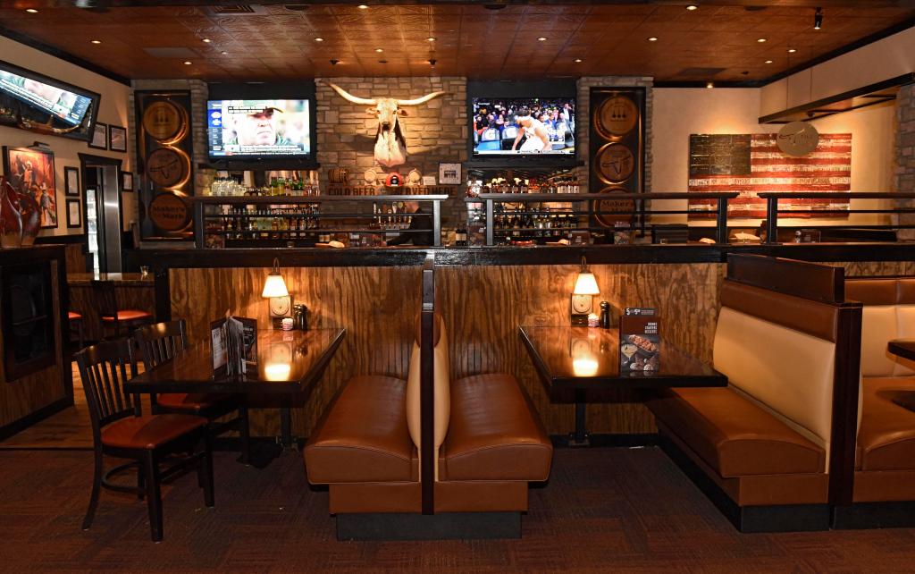 Interior of LongHorn Steakhouse with a bar and television featuring celebrity Mike McCarthy on screen