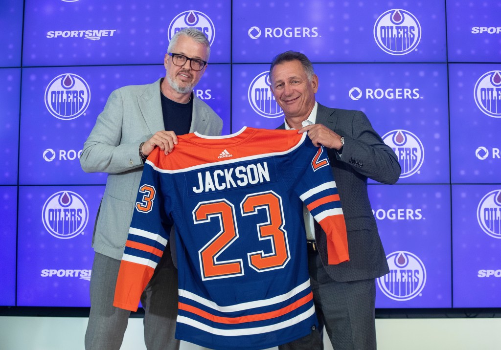 Jeff Jackson, left, new CEO of Hockey Operations for the Edmonton Oilers, and president of hockey operations Ken Holland hold up a jersey to announce the new CEO during a press conference in Edmonton, Thursday, Aug. 3, 2023.