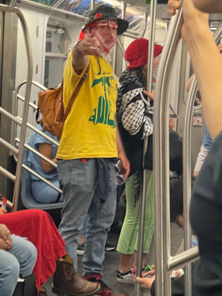 A Jewish man in a yellow shirt holding a scarf in a subway, subjected to hate by a masked protester