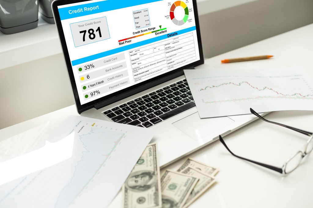 computer with credit score on screen with graphs and money on the table