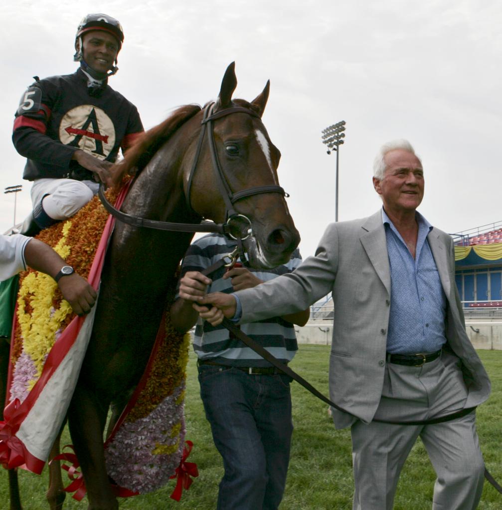 Royal Challenger owner Frank Stronach and jockey Patrick Husbands leads their horse to the winner's circle after winning the Breeders' Stakes on Aug. 6, 2006.