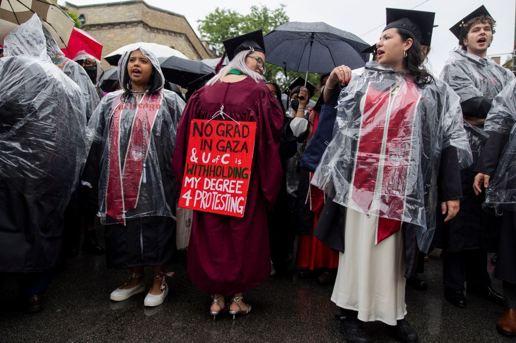 Kelly Hui, a University of Chicago student, showing sign at a rally supporting Palestinians, surrounded by fellow students in graduation gowns holding umbrellas