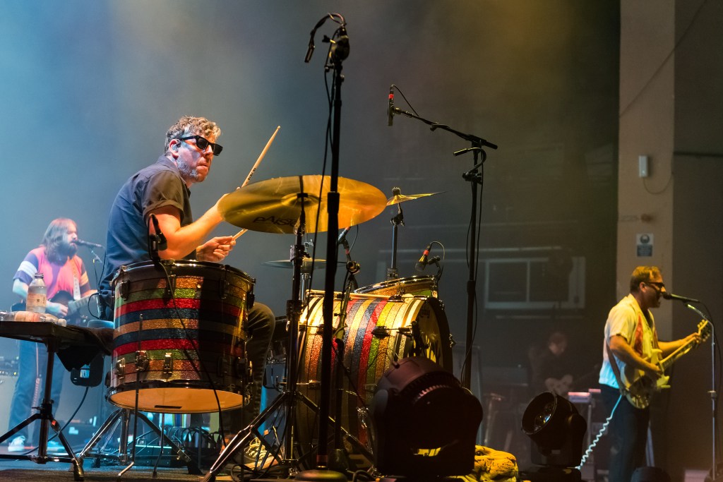 Three members of the rock band The Black Keys play drums, a guitar and a keyboard on stage.