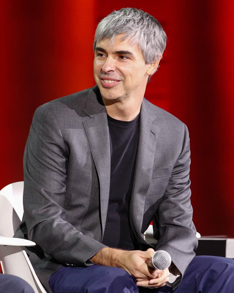 Larry Page, a founder of Google, sitting holding a microphone.