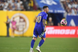 Lionel Messi in a blue uniform kicking a soccer ball