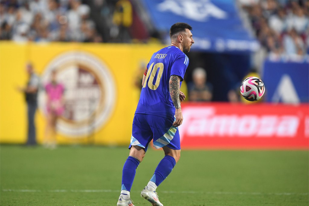 Lionel Messi in a blue uniform kicking a soccer ball