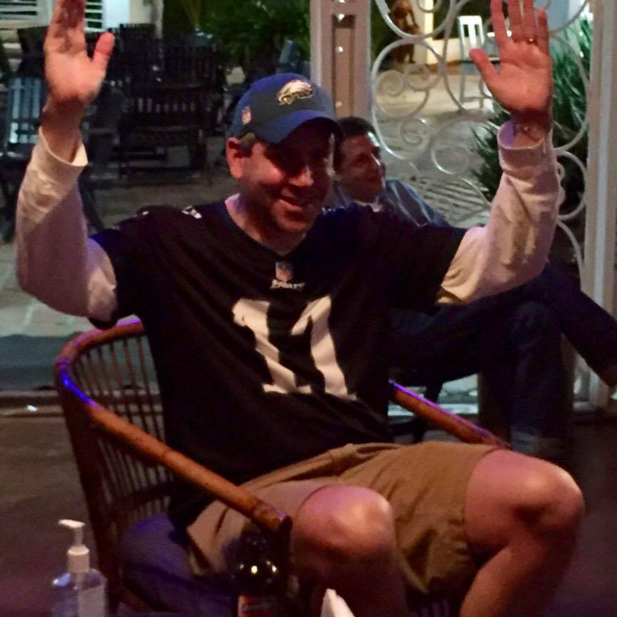 Comedian Chip Leighton sitting in a chair with his hands raised, discussing his humorous rules for parenting teenagers