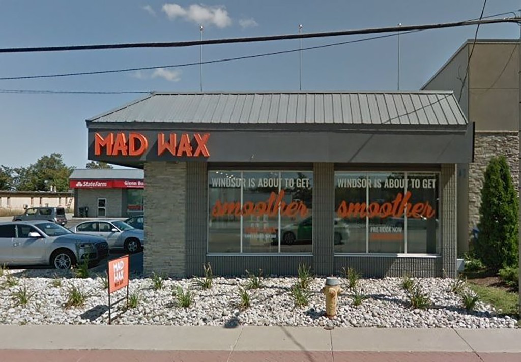 The front of a grey, one-story building that says, "Mad Wax" in orange.