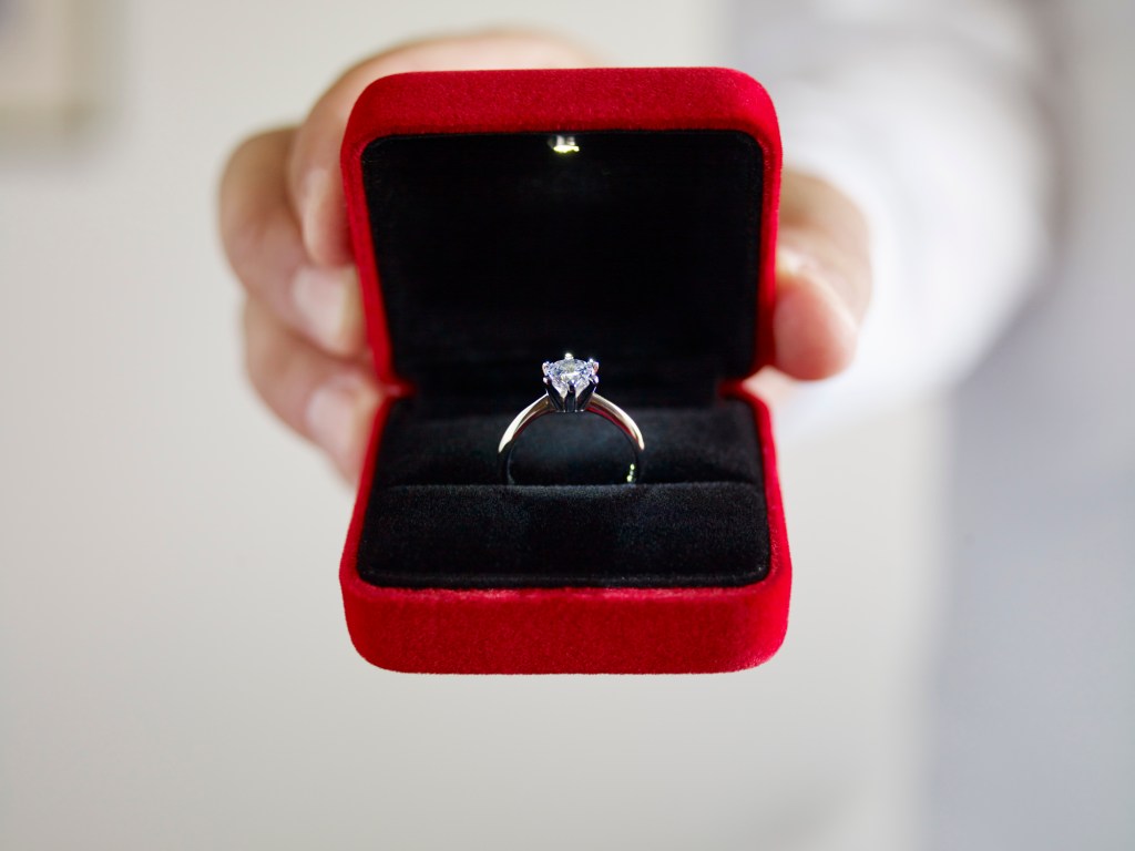 Man in NYC jeweler opening up a box with a diamond engagement ring