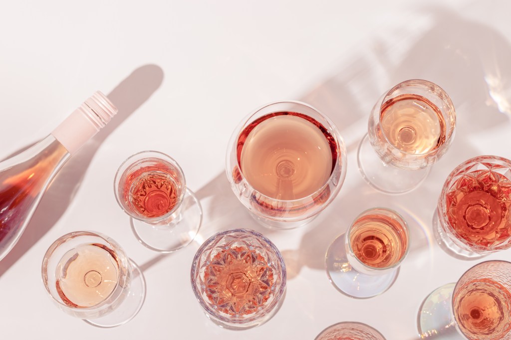 Top view of many glasses and a bottle of rose wine on a light table during a summer party
