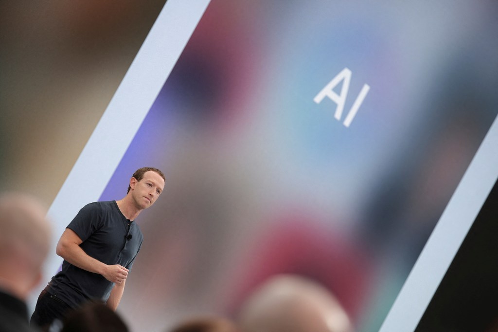 Meta CEO Mark Zuckerberg delivering a speech with artificial intelligence acronyms displayed on a large screen behind him at the Meta Connect event